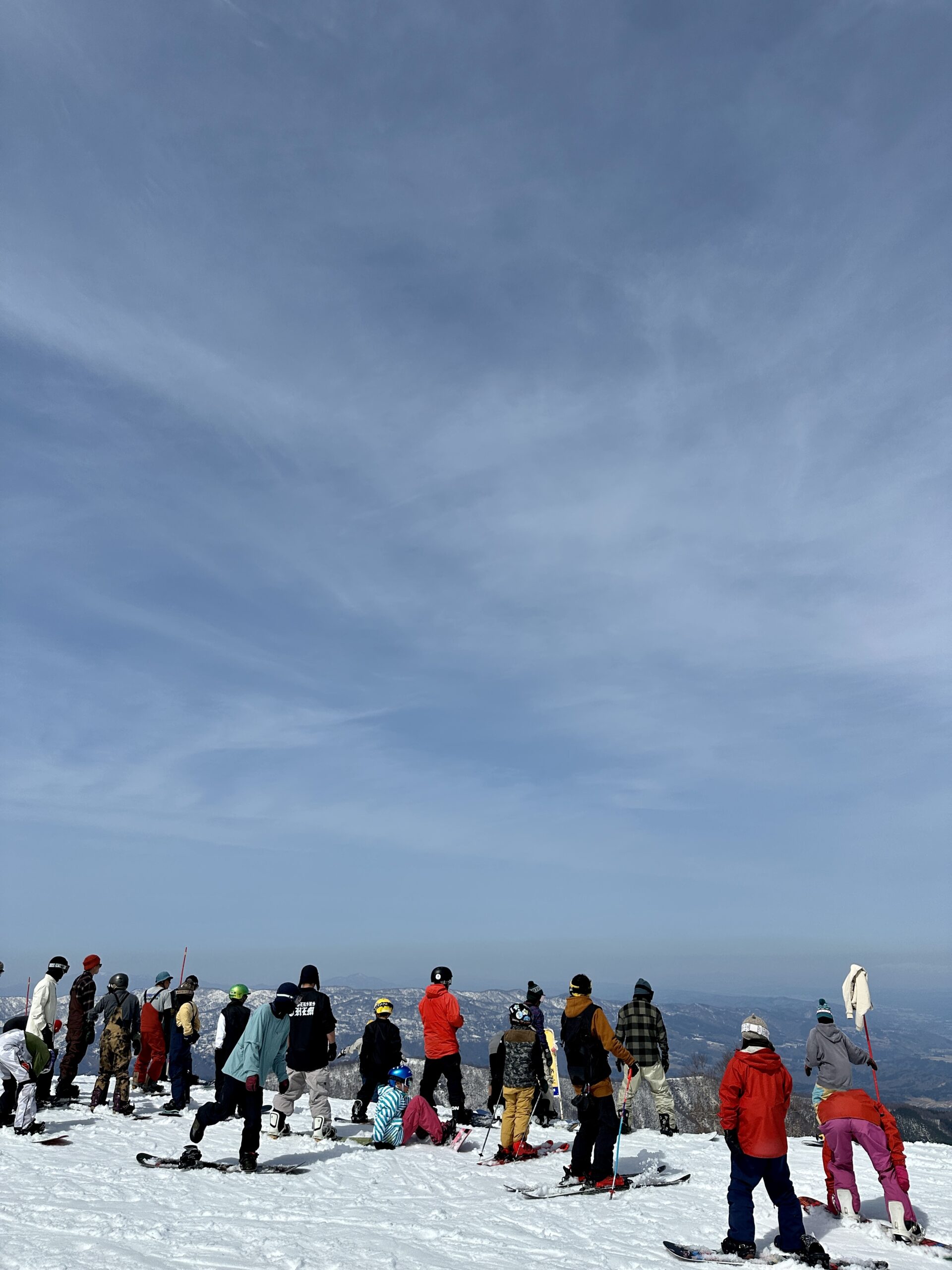 Skiers and snowboarders enjoying the clear sky weather with scenic views from Yamabiko 